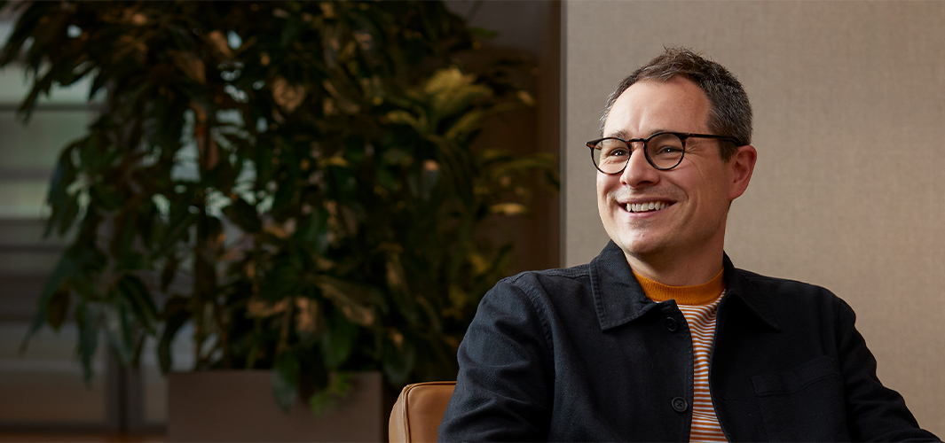 Dan이 안락의자에 앉아 미소를 지으며 자신의 오른쪽의 있는 누군가를 바라보고 있음.