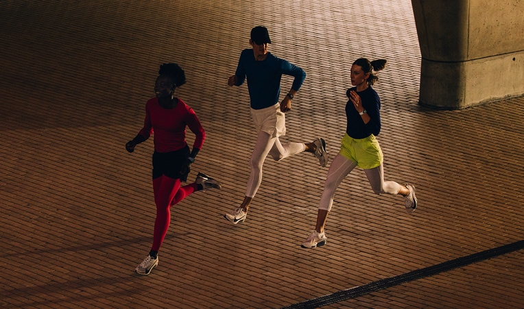 Žena má nasazené Apple Watch Series 11 a protahuje se na podlaze, na obrazovce je Cvičení, Vychladnutí, Aktivita, Kroužky aktivity