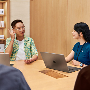 Apple Store employee with a MacBook interacts with a person.