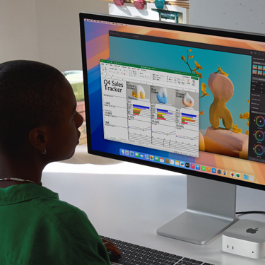 Una mujer sentada en un escritorio trabaja en una hoja de cálculo de Excel en una Mac. La hoja de cálculo de Excel es un registro de ventas del cuarto trimestre. Detrás de la ventana con la hoja de cálculo de Excel hay una ventana de Pixelmator Pro.