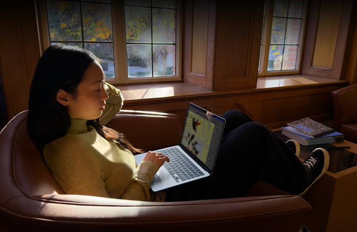 Osoba siedząca na krześle i korzystająca z MacBooka Air