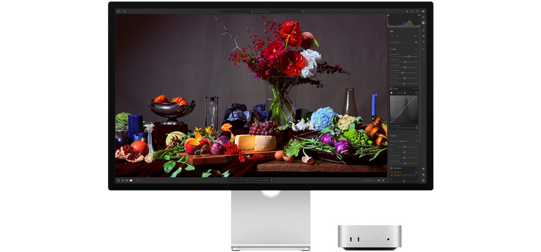 A high-contrast image of a table with various plates of food and a bouquet against a dark background, showcasing how True Tone adjusts color temperature.